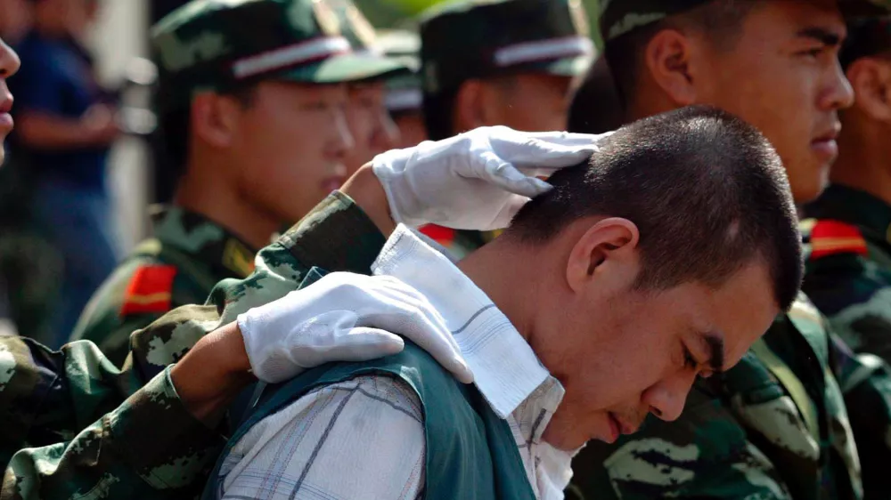A Chinese paramilitary officer keeps the head of a drug dealer bowed during a public sentencing to mark International Day against Drug Abuse and Illicit Drug Trafficking in Hangzhou, eastern China's Zhejiang province, Monday, June 26, 2006. Chinese drug control officials said Thursday their yearlong war on drugs has severely squeezed heroin supplies from the Golden Triangle. Officials also announced the arrest of some 46,000 drug suspects and the seizure of some 6.9 tons of heroin last year. During the trial in Hangzhou, 20 drug dealers were sentenced today with three given the death penalty and executed soon after. (AP Photo) ** CHINA OUT **