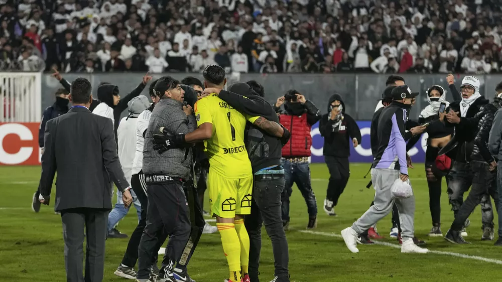 Goalkeeper Brayan Cortes of Chile's Colo Colo confronts fans who invaded the field during a Copa Libertadores Group E soccer match against Brazil's Fortaleza at the Monumental stadium in Santiago, Chile, Thursday, April 10, 2025. (AP Photo/Esteban Felix)