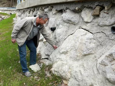 Boris Štupar pokaže na vidne razpoke, ki jih je na povsem novi škarpi naredila teža tovornjakov, svoje pa je dodala še voda. Foto: Tomaž Skale