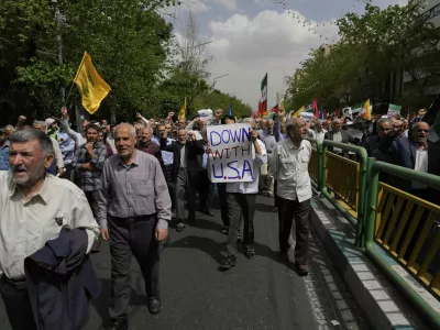 A demonstrator carries an anti-U.S. placard in an anti-Israeli rally after the Friday prayer in Tehran, Iran, Friday, April 11, 2025. (AP Photo/Vahid Salemi)