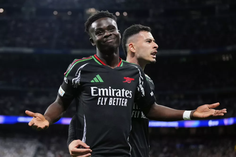 Arsenal's Bukayo Saka celebrates with Gabriel Martinelli, right, after scoring the opening goal during the Champions League quarterfinals second leg soccer match between Real Madrid and Arsenal at the Santiago Bernabeu stadium in Madrid, Wednesday, April 16, 2025. (AP Photo/Manu Fernandez)
