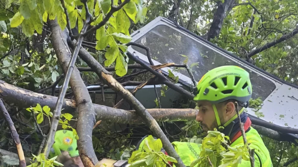 In this photo released by the Italian Alpine and Speleological Rescue Corps on Thursday, April 17, 2025, rescuers reach for the smashed gondola of the Mt. Faito cable car near Naples in southern Italy.