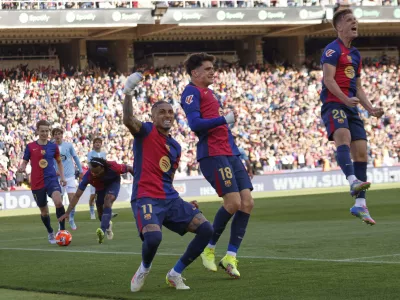 Barcelona's Raphinha, centre left, celebrates with teammates after scoring his side's fourth goal during a Spanish La Liga soccer match between Barcelona and Celta de Vigo at the Lluis Companys Olympic stadium in Barcelona, Spain, Saturday, April 19, 2025. (AP Photo/Joan Monfort)