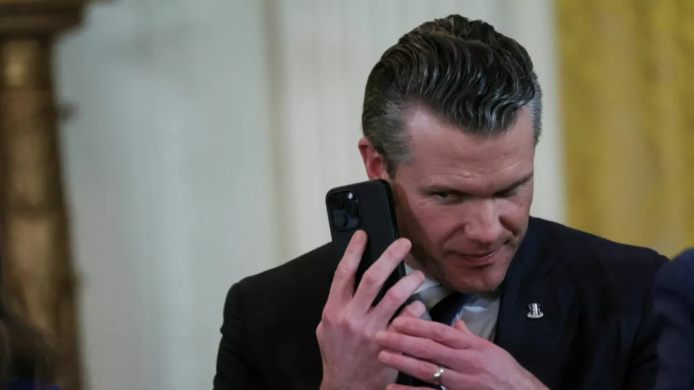 FILE PHOTO: U.S. Defense Secretary Pete Hegseth uses a phone as he attends a joint press conference of U.S. President Donald Trump and Israeli Prime Minister Benjamin Netanyahu in the East Room at the White House in Washington, U.S., February 4, 2025. REUTERS/Leah Millis/File Photo