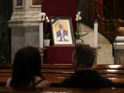 A couple sits near a portrait of Pope Francis, following his death, in the Catholic Cathedral of Saint Dionysius the Areopagite, in Athens, Greece, April 22, 2025. REUTERS/Louisa Gouliamaki