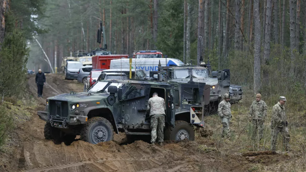 U.S. soldiers gather near military and other vehicles parked at a training range in Pabrade, north of the capital Vilnius, Lithuania on Thursday, March 27, 2025. (AP Photo/Mindaugas Kulbis)