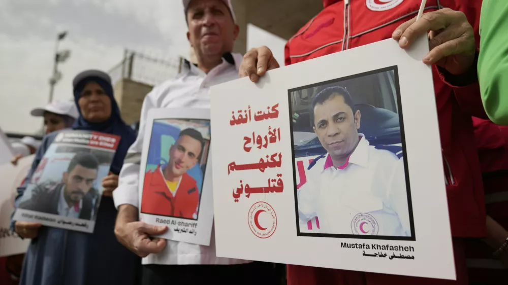 Paramedics from the Palestine Red Crescent Society, PRCS, one carrying a poster that reads "I was saving lives but they killed me," hold signs to honor members of medical missions who lost their lives while carrying out their humanitarian duty, in front of their headquarters in the West Bank city of Ramallah, Wednesday, April 23, 2025. (AP Photo/Nasser Nasser)