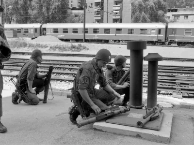 ﻿Pripadniki specialne enote milice med napovedjo letalskega napada na železniški postaji na Jesenicah 2. julija 1991. 