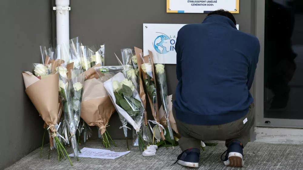 A man pays his respect next to flowers in front of the Notre-Dame-de-Toutes-Aides private school the day after one high school student was killed and three others injured in a stabbing attack by a 15-year-old boy, in Nantes, France, April 25, 2025. REUTERS/Stephane Mahe
