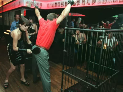 A waitress at La Nouvelle Justine paddles a customer at the S&M restaurant in New York Monday night, Aug. 11, 1997. The customer, who declined to give his name, was treated to the  spanking from the "special menu" by friends who took him to the restaurant after his bachelor party earlier in the evening. (AP Photo/Emile Wamsteker)