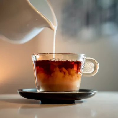 A close-up shot of a poring milk in a hot tea. / Foto: Wirestock
