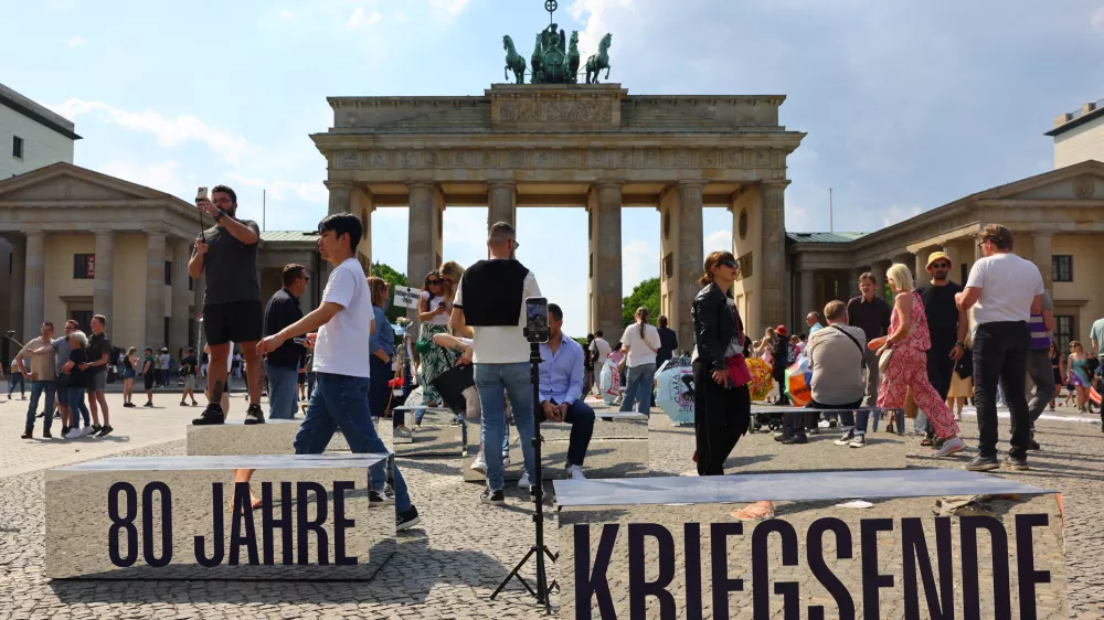 People walk beside mirrored blocks reading, "80 years of the end of the war", in front of Brandenburg Gate to mark the end of World War Two in Europe 80 years ago in Berlin, Germany, May 2, 2025. REUTERS/Fabrizio Bensch