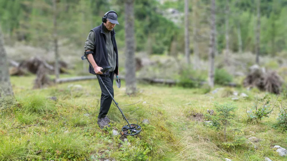 Man on a treasure hunt with a recreational metal detector, shovel and headphones. Electronic treasure finder. Blurred background and copy space / Foto: Alemasche72