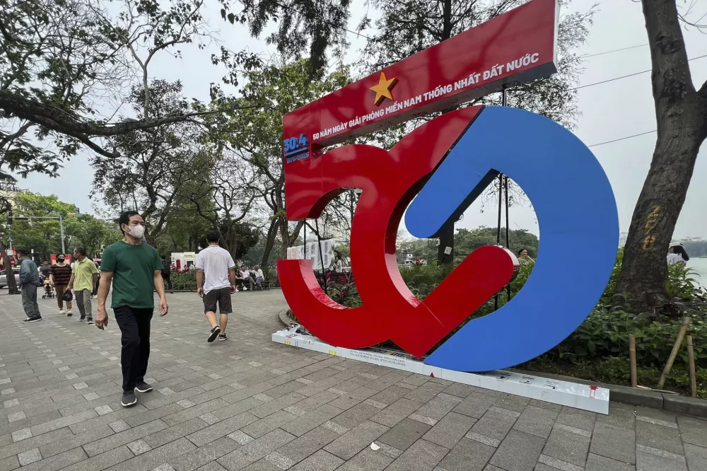 A man walks past a structure celebrating the 50th Anniversary of the end of the Vietnam War in Hanoi, Vietnam, Friday, April 25, 2025. (AP Photo/Lorian Belanger)