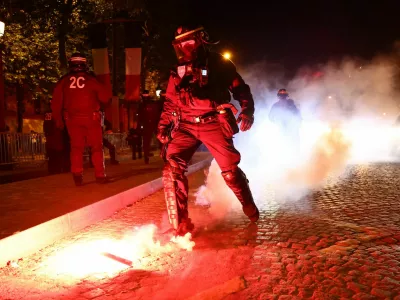Soccer Football - Champions League - Fans celebrate after Paris St Germain qualifies for the final - Paris, France - May 7, 2025 A police officer puts out a flare during the Paris St Germain fans celebration after reaching the final near the Champs Elysees avenue REUTERS/Abdul Saboor