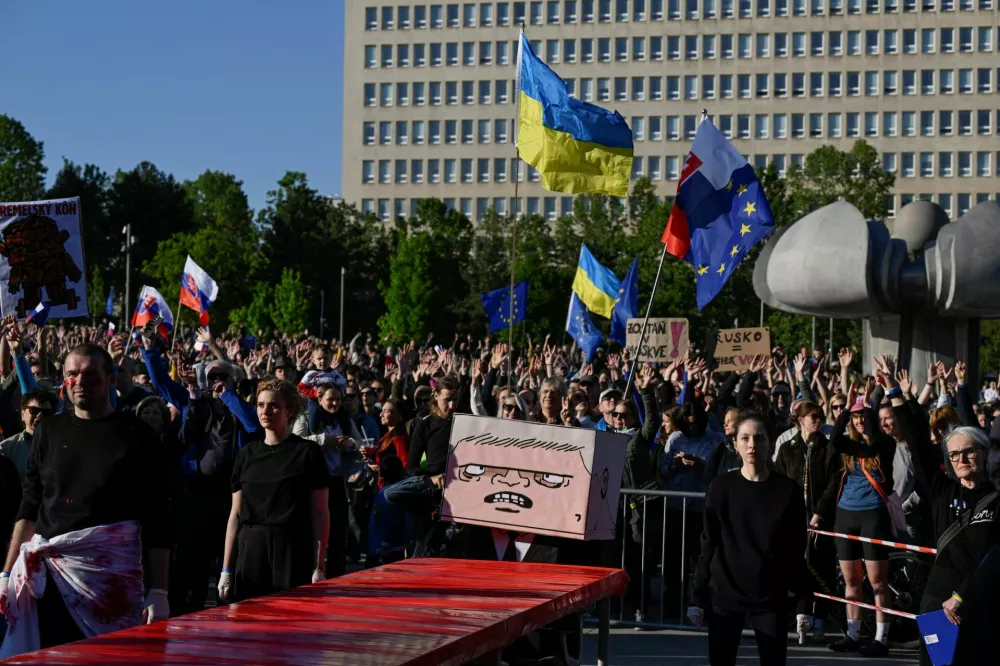 A figure with a box painted with a cartoon depicting Slovakian Prime Minister Robert Fico sits at a table covered in red material, representing blood, at an art performance held during an anti-government protest, in Bratislava, Slovakia, May 9, 2025. REUTERS/Radovan Stoklasa