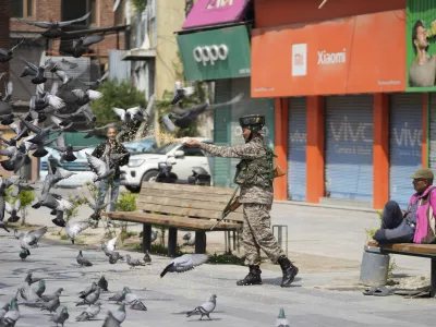 An Indian soldier feeds pigeons at a market, day after India and Pakistan agreed to a ceasefire Saturday following U.S.-led talks to end the most serious military confrontation between the nuclear-armed rivals in decades, in Srinagar, in Indian controlled Kashmir, Sunday, May 11, 2025.(AP Photo/Mukhtar Khan)