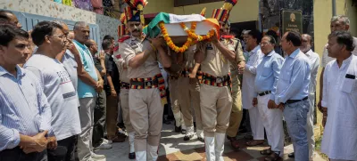 Policemen carry the body of Raj Kumar Thapa, a senior government official who was killed in a cross-border shelling between India and Pakistan, as relatives and neighbours mourn during his funeral in Roop Nagar, Jammu May 11, 2025. REUTERS/Adnan Abidi
