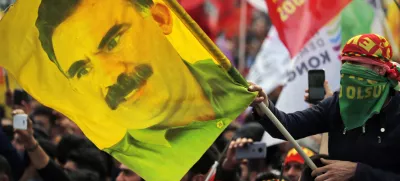FILE - In this file photo dated Wednesday, March 21, 2018, a youth holds a flag with the image of Abdullah Ocalan, the jailed leader of the rebel Kurdistan Workers' Party, or PKK, in Istanbul, Turkey. (AP Photo/Lefteris Pitarakis, File)