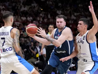 Slovenia's Luka Doncic drives between Greece's Giannoulis Larentzakis, right, and Vasileios Toliopoulos during an Acropolis tournament basketball match, at the Peace and Friendship indoor stadium at Athens' port city of Piraeus, Greece, Saturday, July 6, 2024. (AP Photo/Petros Giannakouris)