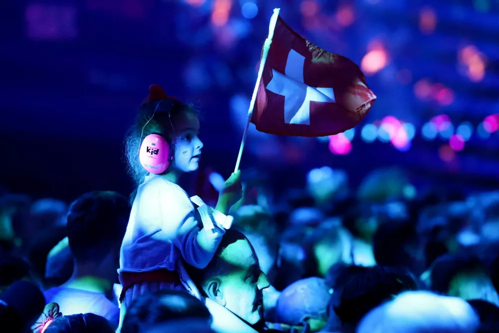 A child holds a Swiss flag as people wait for the start of the first semi-final of the 2025 Eurovision Song Contest, in Basel, Switzerland, May 13, 2025. REUTERS/Denis Balibouse