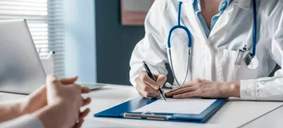Doctor sitting at desk and writing a prescription for her patient / Foto: Demaerre