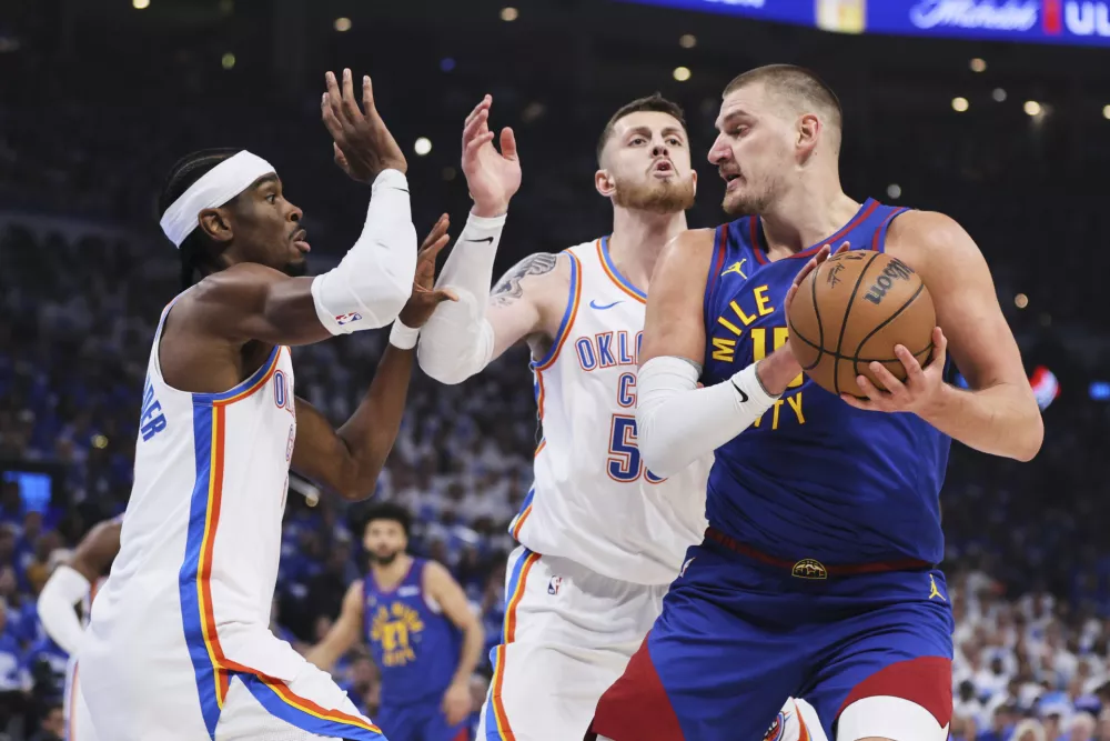 Denver Nuggets center Nikola Jokic, right, works for a shot as Oklahoma City Thunder's Shai Gilgeous-Alexander, left, and Isaiah Hartenstein (55) defend in the first half of Game 5 of an NBA basketball second-round playoff series Tuesday, May 13, 2025, in Oklahoma City. (AP Photo/Nate Billings)