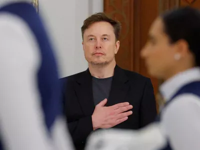 Tesla CEO Elon Musk holds his hand on his heart as the U.S. national anthem is played at a state dinner hosted by Qatar's Emir Tamim bin Hamad Al Thani during a visit by U.S. President Donald Trump, at Lusail Palace in Lusail, Qatar, May 14, 2025. REUTERS/Brian Snyder