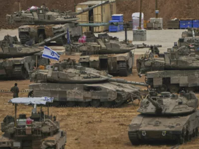 Israeli soldiers work on tanks and APCs at a staging area near the border with the Gaza Strip, in southern Israel, Thursday, May 15, 2025. (AP Photo/Ariel Schalit)