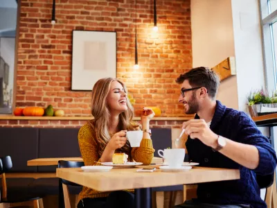 ﻿Couple of young people drinking coffee and eating cake in a stylish modern cafeteria