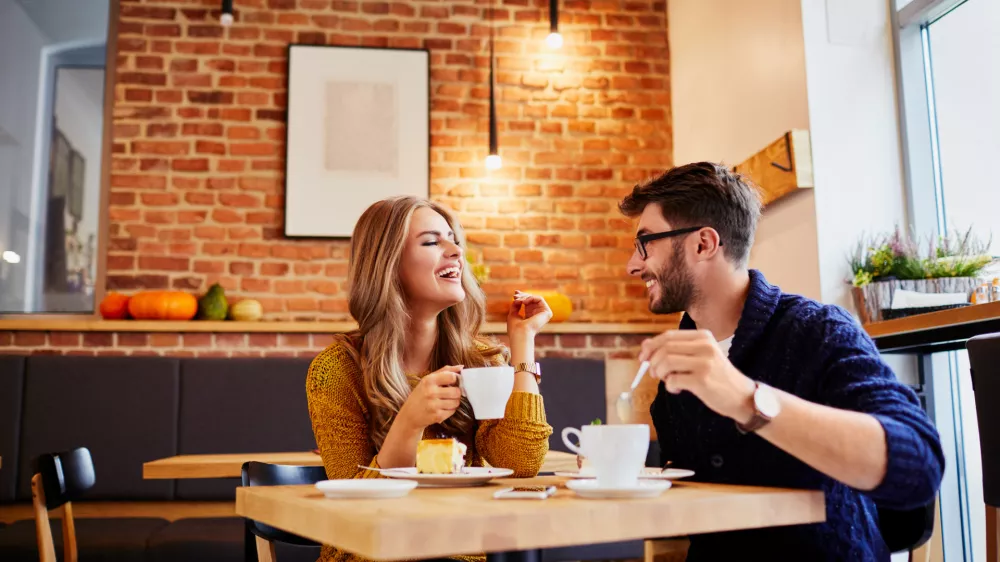 ﻿Couple of young people drinking coffee and eating cake in a stylish modern cafeteria