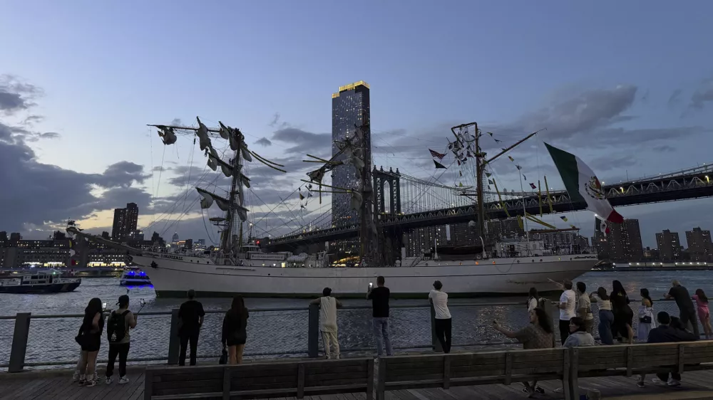 Pedestrians walking along Brooklyn Bridge Park look on as a masted Mexican Navy training ship sits stranded near the Manhattan Bridge after colliding with the Brooklyn Bridge, Saturday, May 17, 2025, in New York. (Nick Corso via AP)