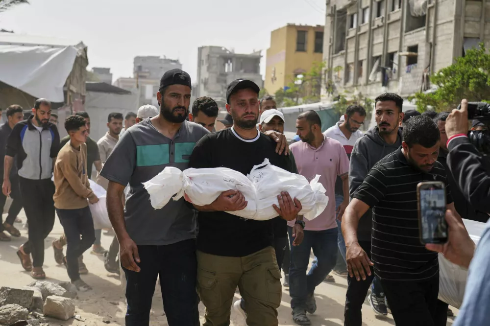 Saleh Zenati, carries the body of his infant nephew Khalid Zenati killed in an Israeli army airstrike, during his funeral in Khan Younis, Gaza Strip, Sunday, May 18, 2025. (AP Photo/Abdel Kareem Hana)