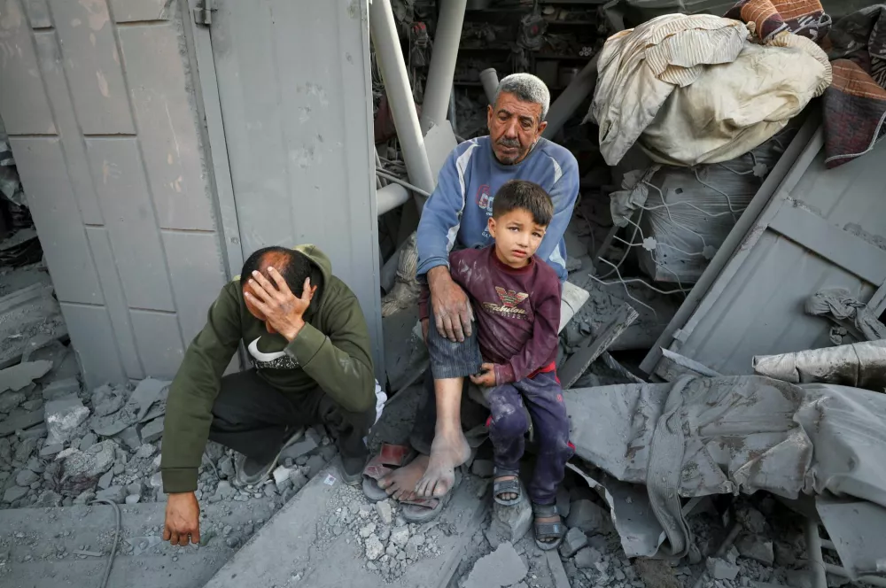 Palestinians sit at the site of an Israeli strike on a house, in Jabalia, northern Gaza Strip May 18, 2025. REUTERS/Mahmoud Issa