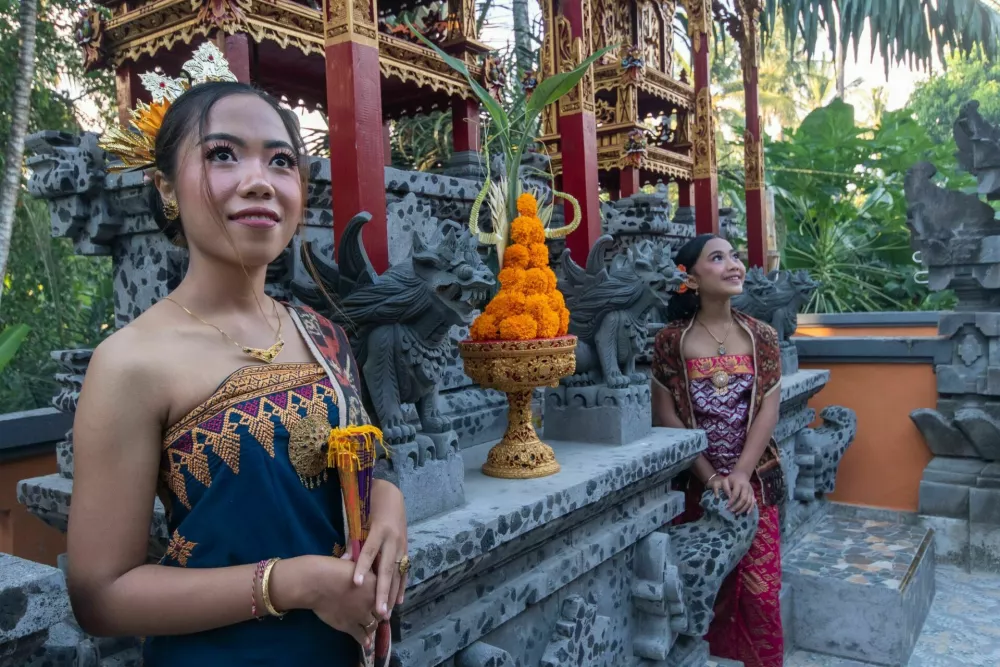 Portrait of two young girls with traditional costume with offering in bali temple. / Foto: Acemason