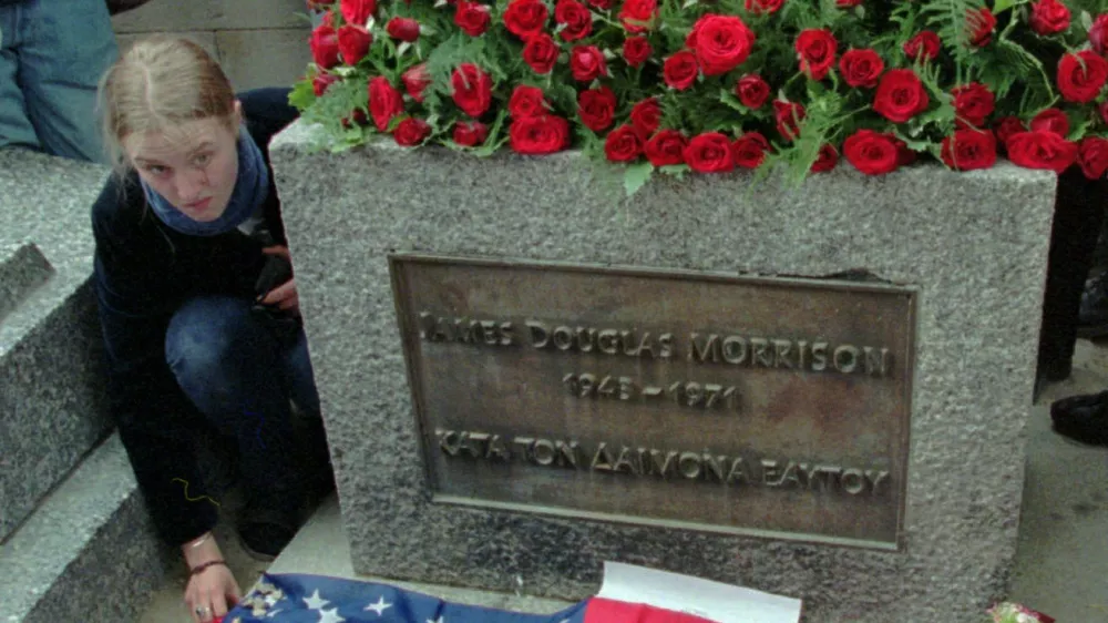 A fan of the Doors' lead singer Jim Morrison lays out an American flag with the likeness of the rock poet at his gravesite in Pere Lachaise Cemetery in Paris Wednesday July 3,1996 the day of the 25th anniversary of the rock singer's death. Many fans from Europe, the United States and Japan bearing candles gathered to pay homage to the dead rock star who has gained a cult status. (AP Photo/Michel Lipchitz)