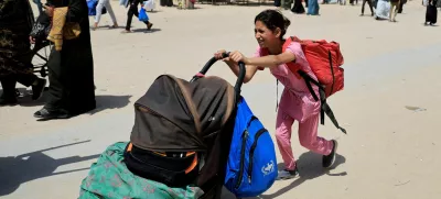 A girl pushes a stroller with belongings as Palestinians flee their homes after the Israeli military issued orders for evacuation from eastern Khan Younis, in the southern Gaza Strip, May 19, 2025. REUTERS/Hatem Khaled   TPX IMAGES OF THE DAY