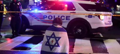 A man, with an Israeli flag with a cross in the center, kneels next to emergency personnel working at the site where, according to the U.S. Homeland Security Secretary, two Israeli embassy staff were shot dead near the Capital Jewish Museum in Washington, D.C., U.S. May 21, 2025. REUTERS/Jonathan Ernst  TPX IMAGES OF THE DAY