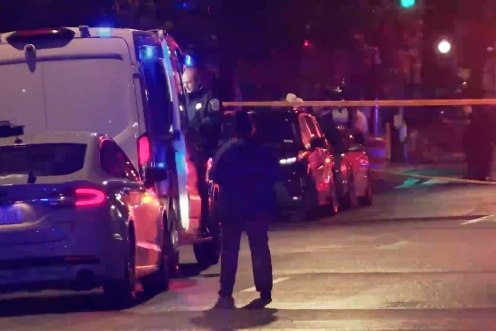 In this image taken from video provided by WJLA, a spectator watches as law enforcement works the scene after two staff members of the Israeli embassy in Washington were shot and killed outside the Capital Jewish Museum on Wednesday, May 21, 2025, in Washington. (WJLA via AP)