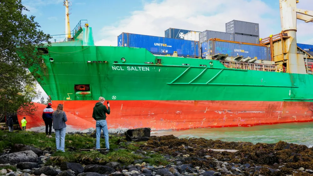People stand near a container ship, which almost hit a house, in Trondheim, Norway, May 22, 2025. NTB/Jan Langhaug/via REUTERS  ATTENTION EDITORS - THIS IMAGE WAS PROVIDED BY A THIRD PARTY. NORWAY OUT. NO COMMERCIAL OR EDITORIAL SALES IN NORWAY.