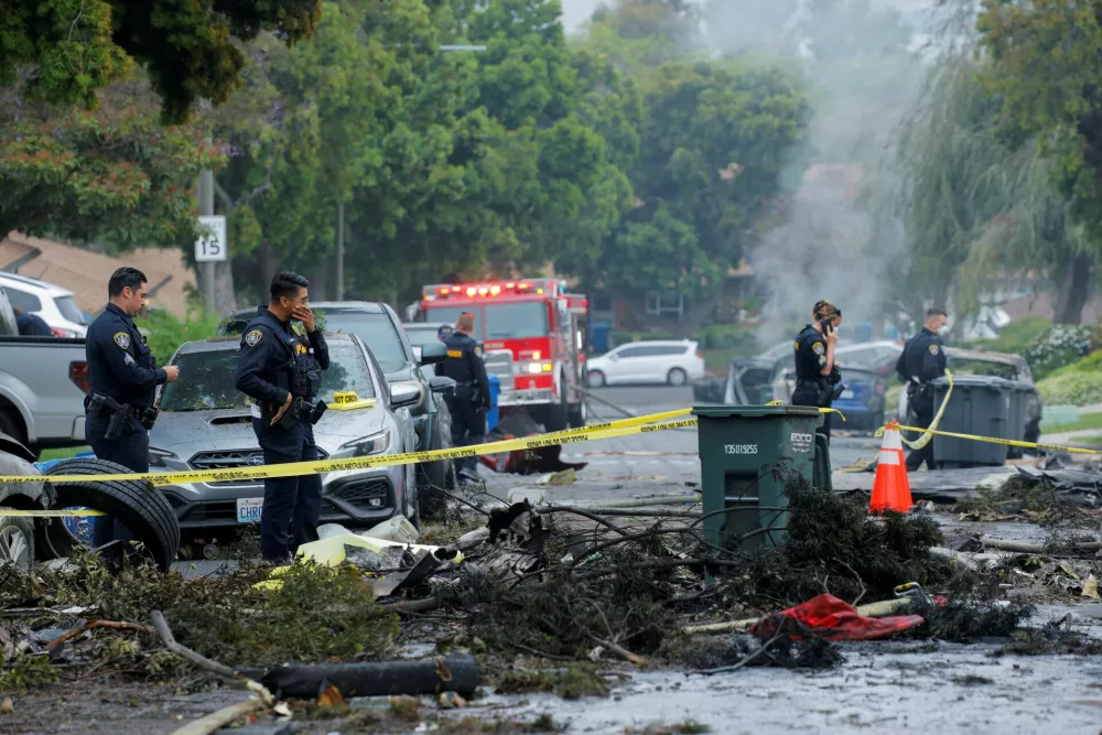 Emergency personnel work at the crash scene on a street, after a small civilian aircraft went down in a military neighborhood in San Diego, California, U.S. May 22, 2025. REUTERS/Mike Blake