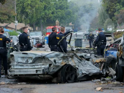 Emergency personnel work at the crash scene on a street, after a small civilian aircraft went down in a military neighborhood in San Diego, California, U.S. May 22, 2025. REUTERS/Mike Blake