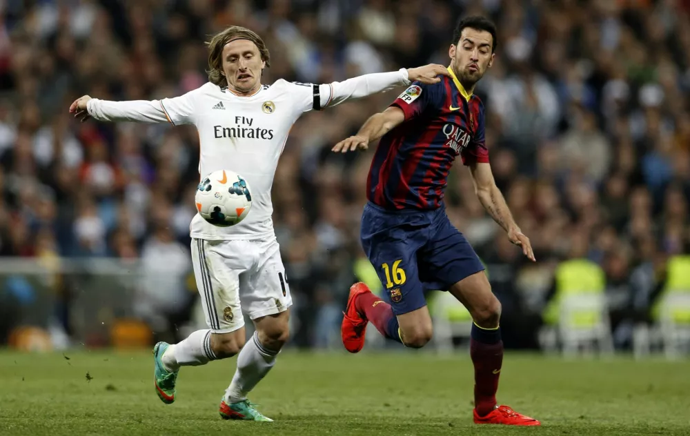 Real Madrid's Luka Modric (L) fights for the ball against Barcelona's Sergio Busquets during La Liga's second 'classic' soccer match of the season at Santiago Bernabeu stadium in Madrid March 23, 2014. REUTERS/stringer (SPAIN - Tags: SPORT SOCCER)