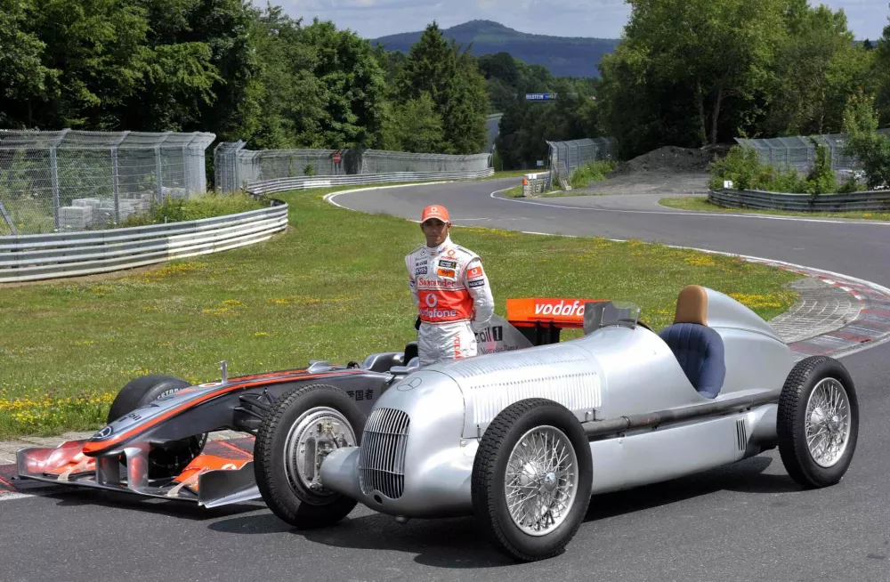 McLaren Mercedes driver Lewis Hamilton of Britain poses with the W25 Silver Arrow, right, and a show car of the McLaren Mercedes F1 racing car MP4-24, left, on the old Nordschleife of the Nuerburgring on Thursday, July 9, 2009, three days prior to the German Formula One Grand Prix at the Nuerburgring racetrack, Germany. The Grand Prix will be held here on Sunday, July 12, 2009. (AP Photo/Gero Breloer)