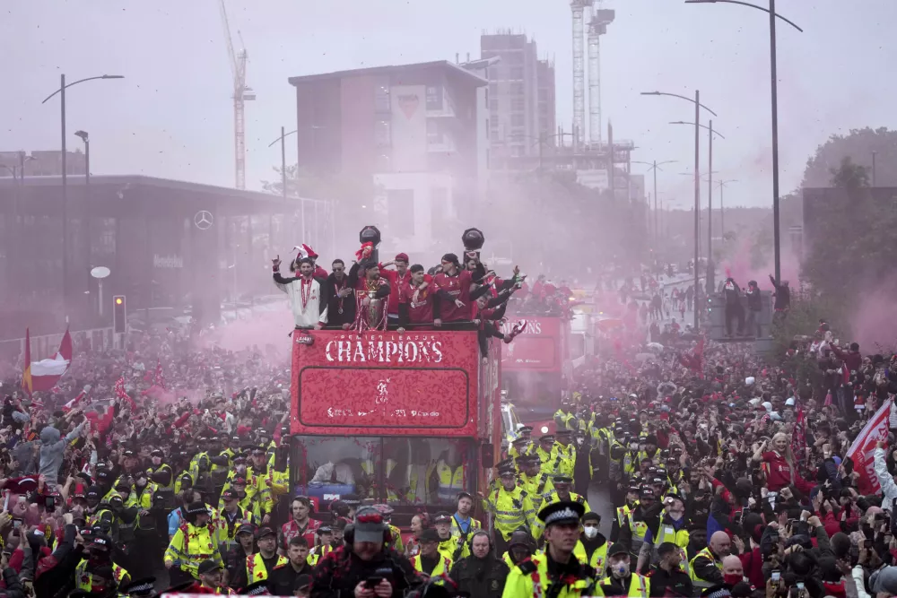 Liverpool players celebrate with the trophy on an open-top bus during the Liverpool FC Premier League victory parade in Liverpool, England, Monday, May 26, 2025.(AP Photo/Jon Super)