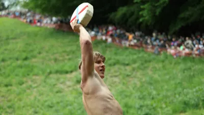 Tom Kopke, from Munich, holds a cheese wheel after winning the first race of the annual Cooper's Hill Cheese-Rolling and Wake competition near Brockworth, Britain, May 26, 2025. REUTERS/Isabel Infantes