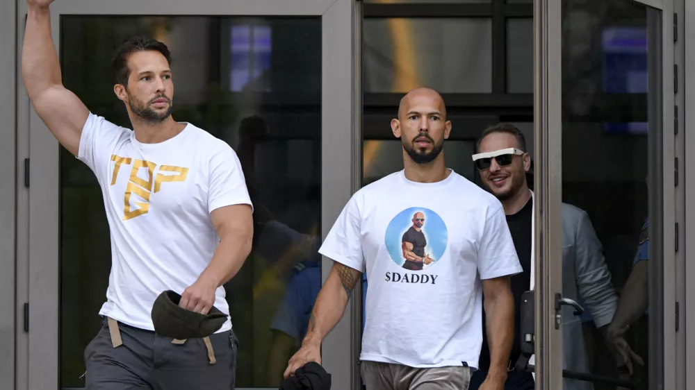 FILE - Andrew Tate, center, and his brother Tristan, left, exit the Bucharest Tribunal after being placed under house arrest, in Bucharest, Romania, Aug. 22, 2024. (AP Photo/Alexandru Dobre, File)