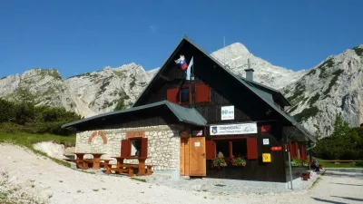 Poštarski dom na Vršiču ima med vsemi vršiškimi postojankami najlepši razgled; na vzpetini pred domom je razgledna plošča z označenimi vrhovi, ki se vidijo. F Kranjska gora