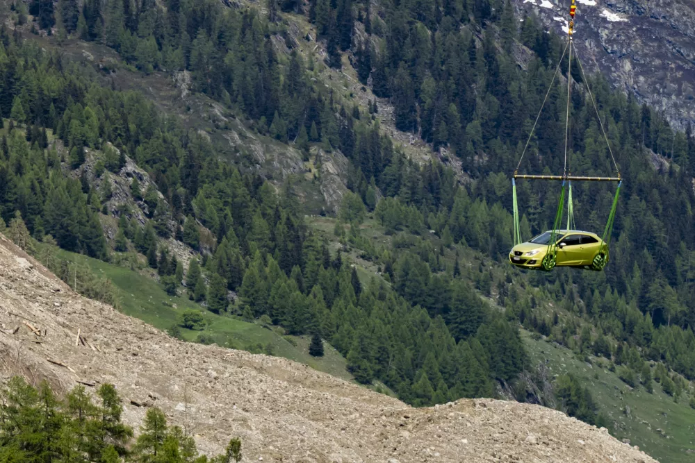 A helicopter evacuates a car from the village of Blatten, Switzerland, Thursday, May 29, 2025, one day after a massive debris avalanche, triggered by the collapse of the Birch Glacier, swept down to the valley floor and demolished large parts of the village. (Jean-Christophe Bott/Keystone via AP)