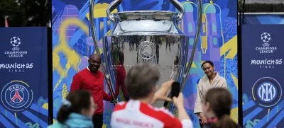 People take pictures at a giant trophy during the opening of the official UEFA fan festival in Munich, Germany, Thursday, May 29, 2025 ahead of the Champions League final soccer match between Inter and PSG. (AP Photo/Matthias Schrader)